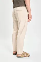Pantalón casual color beige confeccionado con lino y elastano, de corte recto y largo hasta el tobillo.