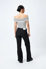 Jean negro de calce flare con cinturón incorporado en la misma tela y silueta ajustada en cadera que se ensancha hacia el ruedo.