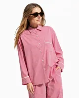 Pijama de dos piezas de algodón a rayas celestes y blancas, compuesto por una camisa de manga larga con botones y ribetes marrones, y un pantalón largo de corte recto con elástico en la cintura.