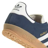 Championes adidas Gazelle de diseño clásico, confeccionados en gamuza azul con las icónicas tres tiras laterales en blanco. Presentan detalles en blanco en el talón y la lengüeta, con el nombre del modelo en dorado y una suela de goma color caramelo.