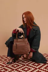 Cartera mochila de diseño versátil, color rosado, confeccionada en material sintético impermeable. Cuenta con doble asa superior, correas ajustables para usar como mochila, compartimento principal con cierre y bolsillo frontal con cierre decorado con tirador largo.