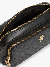 Cartera tipo cámara de poliuretano color negro, con diseño texturizado en bajo relieve con monograma TH, herrajes dorados, cierre de cremallera y correa cruzada extraíble.
