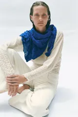 Jersey de cuello redondo y manga larga color azul, con tejido semitransparente de efecto arrugado.