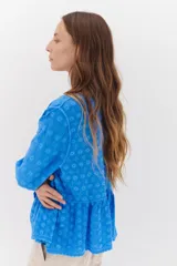 Camisa color crema con bordados florales, escote en V, mangas largas y cierre frontal con botones.