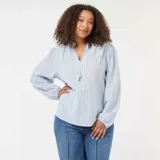 Blusa de corte fluido con estampado de rayas verticales finas en tonos azul y rojo. Presenta cuello redondo con abertura frontal y cordones con borlas, mangas largas abullonadas con puños elásticos y un diseño holgado.