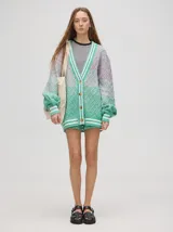 Cardigan tejido de punto con diseño de rombos en degradé de tonos verdes y rosados. Presenta cuello en V, cierre frontal con botones, mangas largas abullonadas con puños elásticos a rayas y un calce oversize.