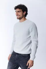 Buzo de tejido de punto con textura de gofre o waffle, color gris melange claro, de cuello redondo y manga larga.