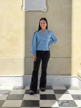 Camisa de jean celeste con cuello redondo, cierre frontal con botones y mangas largas abullonadas con puños ajustados.