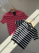 Remera corta de punto con cuello redondo y mangas cortas, a rayas horizontales. Disponible en color rosa con rayas rojas y en color negro con rayas blancas.