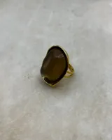 Anillo de diseño llamativo con base dorada y piedra central de resina en tono ámbar con textura orgánica.