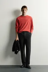 Pantalón negro confeccionado en mezcla de algodón, con cintura elástica, bolsillos frontales y cierre con cremallera y botón.