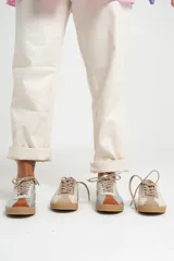 Zapatillas deportivas de cuero color beige con detalles en naranja y suela marrón.