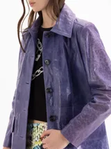 Tapado de cuero ovino color lila, de silueta estructurada y corte evasé. Cuenta con cuello camisero clásico, cierre frontal con botones, un bolsillo superior en el pecho y dos bolsillos inferiores con tapa.