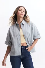 Camisa celeste de corte amplio con mangas cortas con dobladillo.