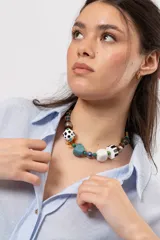 Collar corto de Lanka con abalorios variados, incluyendo cuentas esféricas con lunares, cubos blancos y negros, piezas de piedra turquesa, esferas de porcelana azul y blanca, y detalles metálicos plateados y marrones.