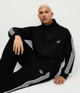 Pantalón deportivo negro con rayas laterales blancas, cintura elástica, bolsillos y estampa localizada en la parte superior.