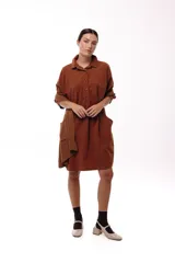 Vestido camisero de silueta amplia y fluida, color verde militar, con cuello camisero, frente abotonado parcial, mangas largas y bolsillos laterales.