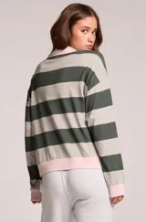 Sweater de rayas horizontales grises y verde oscuro, con cuello polo y escote en V en color rosado, puños y ruedo rosados, y parches bordados en el pecho.