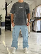 Remera oversize de efecto gastado color celeste, con cuello redondo y mangas cortas. Estampado frontal pequeño con el texto "Top Style" y gran estampado en la espalda con el mismo texto, la frase "Dream big. Work hard. Make it real.", el año "SINCE 2021" y un código de barras.