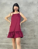 Vestido corto color bordó, con breteles finos que se atan en los hombros, corte recto y falda con volados.