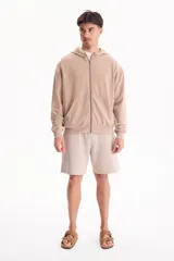 Campera con capucha y cierre frontal, color beige con efecto lavado stone wash, bolsillos tipo canguro y corte oversize.
