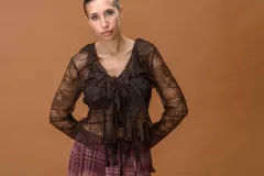 Saco de encaje semitransparente color marrón, con escote en V, volantes frontales, lazo ajustable y mangas largas con terminación acampanada.