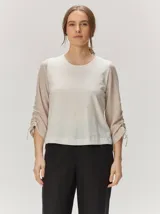 Remera de manga larga color blanco con cuello redondo y detalles fruncidos con lazos en las mangas.