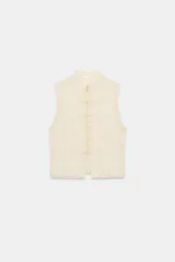 Chaleco beige plisado de tejido de algodón, con cuello mao y cierre frontal con alamares.