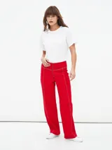 Pantalón de corte recto y tiro alto, color rojo, con costuras decorativas en contraste y cierre frontal con cremallera expuesta.