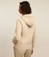 Campera deportiva color beige con cierre frontal de cremallera, capucha ajustable con cordones, mangas largas y bolsillos frontales tipo canguro. Confeccionada en tejido de algodón y poliéster.