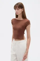 Top ajustado de poliéster color marrón, con mangas cortas, cuello redondo a la base y diseño abierto en los laterales con tiras cruzadas.