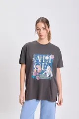 Remera oversize de manga corta, color gris oscuro con efecto gastado, con estampado frontal de Alicia en el País de las Maravillas, incluyendo el texto "ALICE In Wonderland" rodeado de flores.