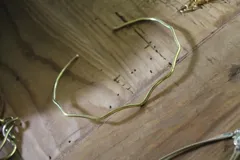 Gargantilla rígida de bronce con diseño ondulado y acabado pulido.