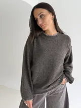 Sweater de punto color gris con cuello redondo, mangas largas y terminaciones con detalle de pespunte en color crudo en el cuello, puños y ruedo.