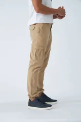 Pantalón cargo de hombre con fit slim, confeccionado en una mezcla de algodón y elastano. Presenta cierre de cremallera y botón, bolsillos laterales tipo cargo, pasa cinto y terminación con puños elásticos en los tobillos.