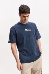 Remera oversize azul marino con efecto lavado, manga corta y cuello redondo. Cuenta con un pequeño estampado gráfico frontal con texto blanco y diseño XL en la espalda.