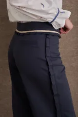 Pantalon de vestir azul marino de corte recto y tiro medio, con detalle de volados en la cintura y cierre frontal con botón.