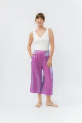 Pantalón de lino con acabado metalizado tornasolado, que refleja tonos entre rosa y lila según la luz. De corte recto y largo ¾, tiene cintura con elástico en la espalda que aporta comodidad y un calce relajado.