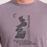 Remera lila de manga corta con estampado gráfico frontal en tonos oscuros que incluye una pila de rocas y texto.