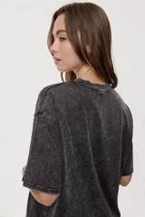 Remera oversized de manga corta y cuello redondo, de color negro con efecto acid wash y aplicación de strass en la parte superior.