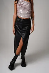 Falda midi negra de ecocuero, tiro alto, con bolsillos delanteros y traseros, abertura frontal, cierre con cremallera, botón y presillas para cinturón.