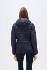 Campera acolchada tipo puffer, color beige claro, con capucha y cierre frontal. Presenta costuras horizontales y un calce entallado.