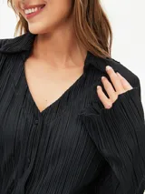 Camisa negra con textura plisada, cuello clásico, escote en V y mangas largas.