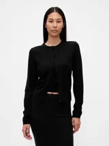 Saco tipo cardigan de punto fino, color negro, con cuello redondo, cierre frontal de botones y mangas largas.