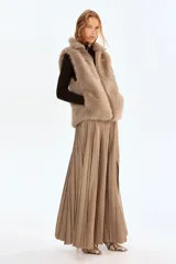 Chaleco de piel sintética con textura suave y efecto peludo, cuello elevado, cierre frontal con cremallera y bajo con elástico oculto para un ajuste abullonado.