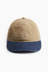 Gorra de sarga color beige con visera azul marino y bordado frontal con el texto "Running Club".