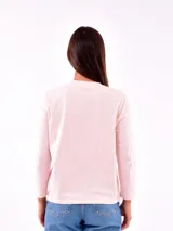 Remera de manga larga color blanco, con cuello redondo y estampa frontal en tono rosado que incluye un diseño de marco con moño y la frase "live simply love sincerely".