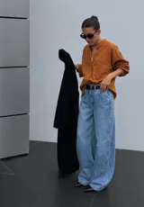 Camisa de sarga color mostaza, de diseño irregular con los costados más largos, mangas largas y corte amplio.