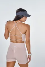 Conjunto deportivo compuesto por un top con espalda de tiras cruzadas y un short de tiro alto con efecto fruncido en la parte trasera. Ambas piezas son de color beige y presentan un diseño ajustado sin costuras.