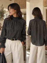 Blusa de seda color rojo terracota con diseño de rayas verticales blancas, cuello smock fruncido y mangas largas amplias con puños elásticos fruncidos.